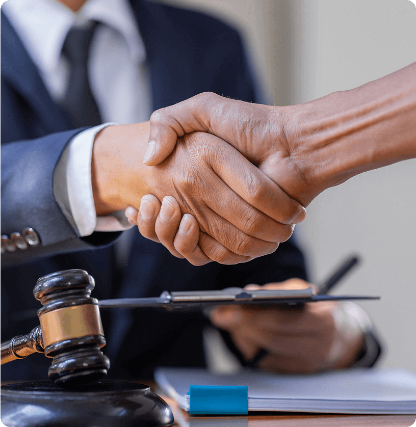 Handshake over desk with gavel and documents.
