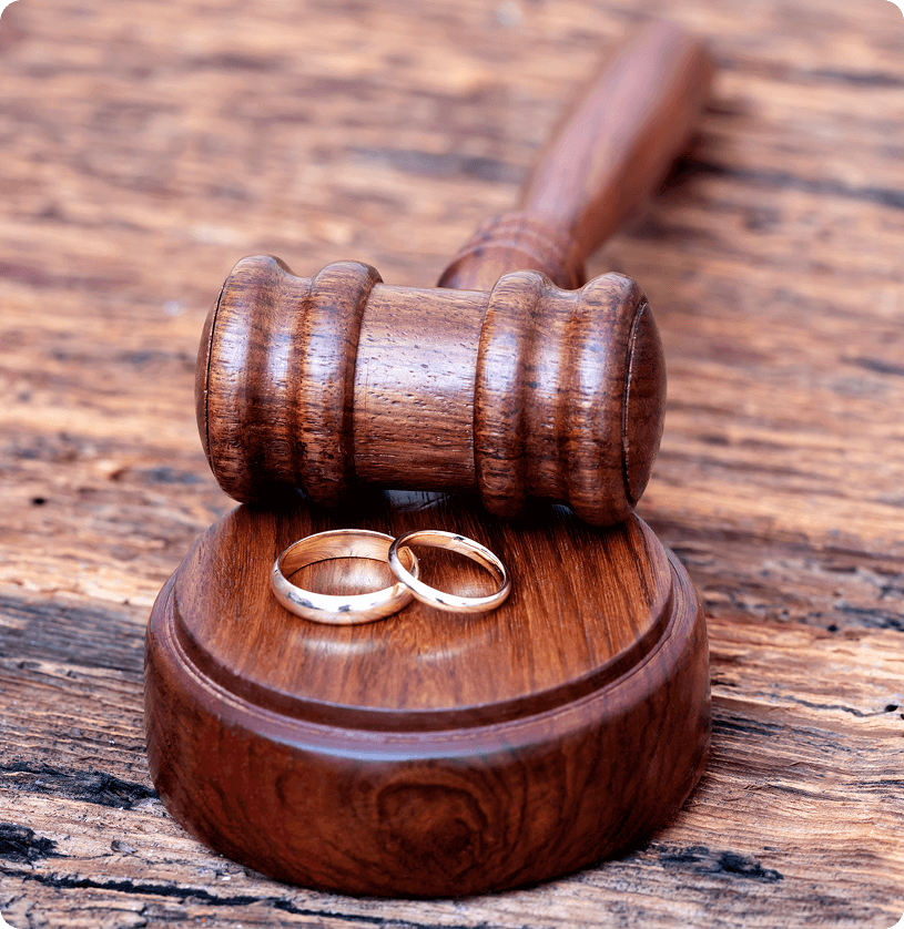 Gavel and wedding rings on wooden surface.
